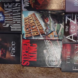 K&ouml;nnte beinhalten: Eine Sammlung von acht B&uuml;chern, die in einem Raster angeordnet sind, darunter Titel wie Strange Highways von Dean Koontz, The Regulators von Richard Bachman, The A to Z Encyclopedia of Serial Killers, The Face von Dean Koontz und The First Days von Rhiannon Frater.