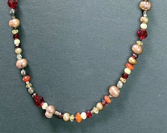 Puede incluir: Un collar hecho de cuentas marrones, naranjas y rojas con un cierre plateado.