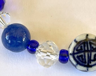 Puede incluir: Un brazalete de cuentas azules y blancas con una cuenta de porcelana azul y blanca con un diseño de caracteres chinos.
