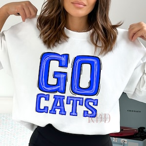 May include: White sweatshirt with a blue and black graphic that says "GO CATS" in a hand-drawn style.