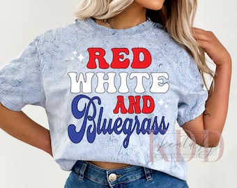 Może przedstawiać: Jasno błękitny t-shirt z napisem "Red White and Bluegrass" w czerwonych, białych i niebieskich literach. Koszulka ma postarzony wygląd.