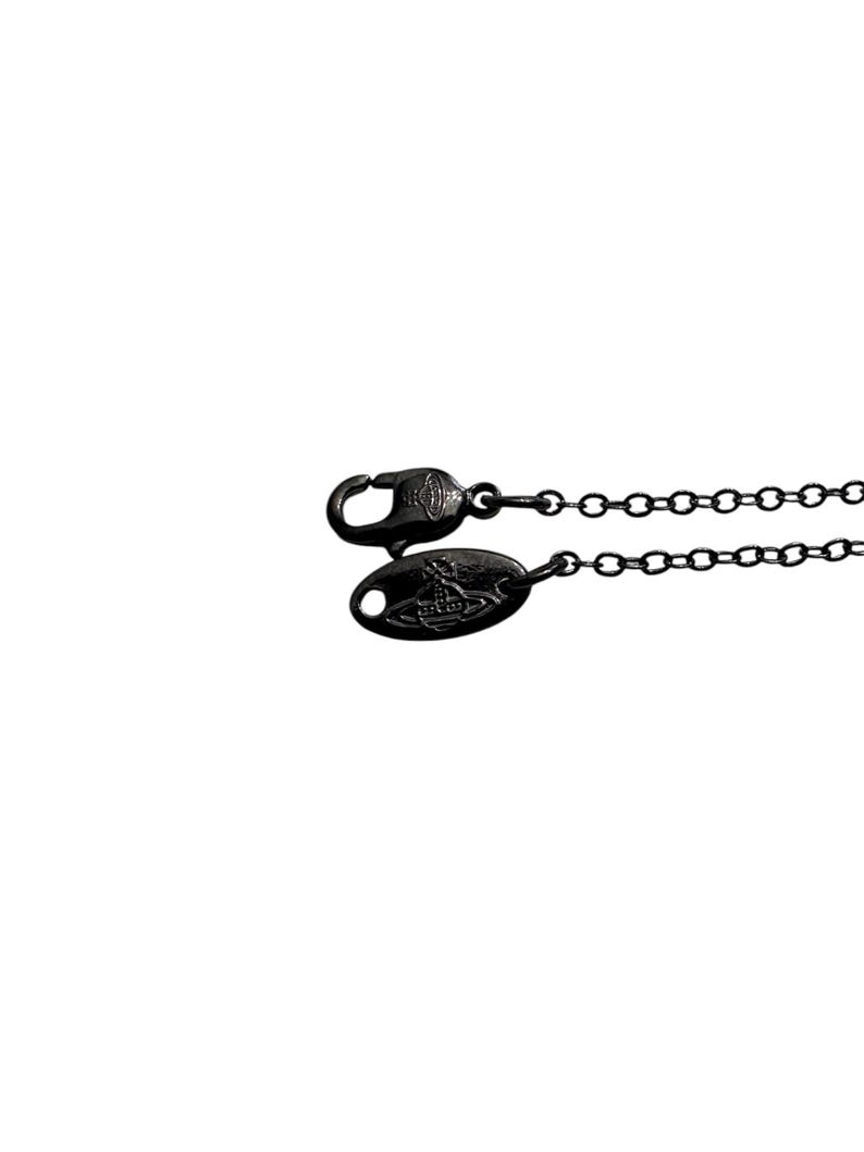 May include: A black metal necklace chain featuring a lobster claw clasp and an oval-shaped metal tag. Both the clasp and the tag are embossed with a small orb logo design. The chain consists of small, uniform circular links in a dark finish.