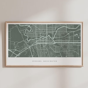 May include: A framed print featuring a detailed map of Spokane, Washington, in a muted green and white color scheme. The city's layout, including streets and waterways, is depicted. The text "SPOKANE, WASHINGTON" is printed at the bottom.