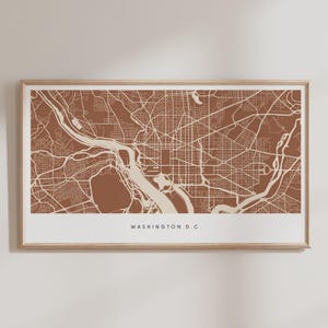 May include: Framed map print of Washington D.C. in a minimalist style. The map features a detailed layout of the city's streets and waterways in shades of brown and beige. The text "WASHINGTON D.C." is printed at the bottom.