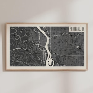Może przedstawiać: Oprawiony wydruk mapy Portland w stanie Oregon. Mapa przedstawia szczegółową siatkę ulic i system rzek w kolorze białym na ciemnoszarym tle. Słowa "PORTLAND, OR" znajdują się w białym prostokącie w prawym górnym rogu.