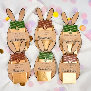 May include: Easter-themed chocolate gifts. Each gift features a brown paper bunny shape with attached ears, holding a small chocolate bar. Text on the gifts includes phrases like "Happy Easter" and "Chocolate Joy". Confetti in the background.