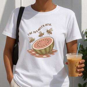 May include: White t-shirt with a watermelon and bees graphic and the text "One in a melon hive."