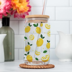 May include: A clear glass drinking jar with a bamboo lid and a straw. The jar has a lemon pattern with yellow lemons and green leaves.