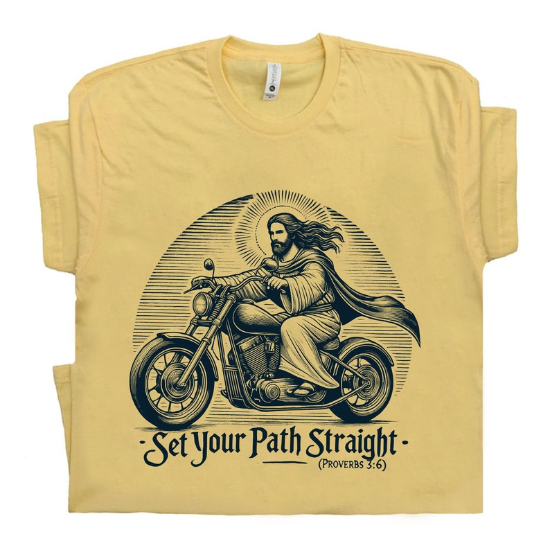 Puede incluir: Una camiseta amarilla con una ilustraci&oacute;n en blanco y negro de Jes&uacute;s conduciendo una motocicleta. El texto "Set Your Path Straight - (Proverbs 3:6)" est&aacute; impreso debajo de la imagen.