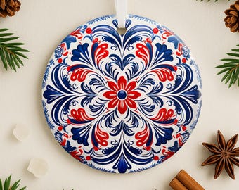 May include: A round, white ornament with a blue and red floral pattern. The ornament has a white ribbon attached to the top.