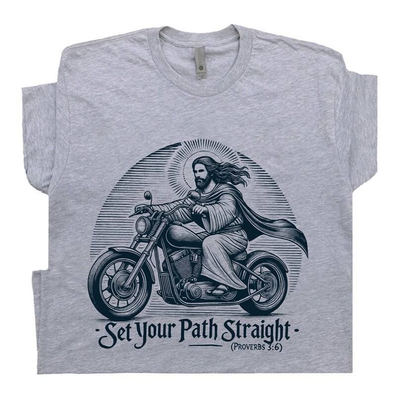 Puede incluir: Una camiseta gris con un gr&aacute;fico de Jes&uacute;s conduciendo una motocicleta. El gr&aacute;fico es de estilo vintage e incluye el texto "Set Your Path Straight - (Proverbs 3:6)"