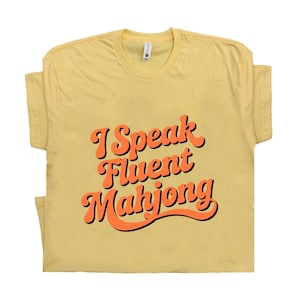 May include: A yellow t-shirt with the text "I Speak Fluent Mahjong" in orange and black lettering.