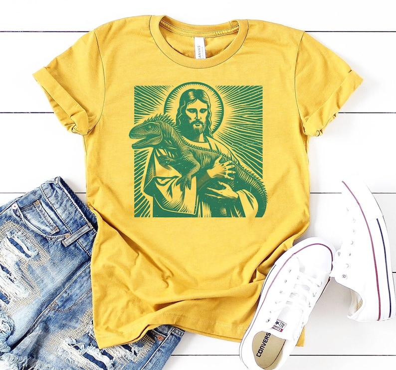 May include: A yellow t-shirt with a green graphic print of Jesus holding a lizard.