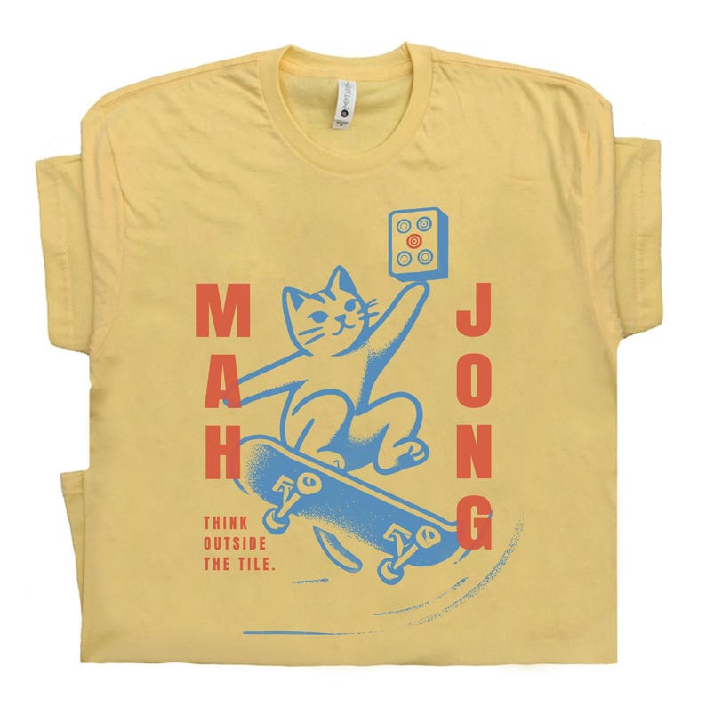 May include: A yellow t-shirt with a blue and red illustration of a cat skateboarding with a mahjong tile. The text "Think outside the tile." is printed below the illustration.