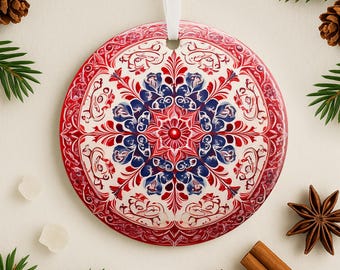 May include: Red, white, and blue Christmas ornament with a detailed floral pattern. The ornament is round and has a white background with red and blue floral designs.