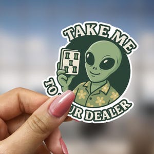 May include: A sticker featuring a green alien holding a card with symbols. The alien is wearing a floral shirt. Text on the sticker reads "TAKE ME TO YOUR DEALER" in white and green.