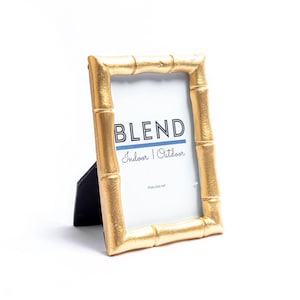 May include: Gold bamboo picture frame with a white mat and the text "BLEND Indoor | Outdoor" on the mat.