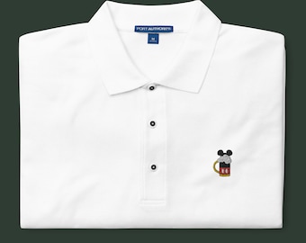 May include: White polo shirt with a small embroidered image of Mickey Mouse holding a beer stein. The shirt has a blue tag that says "PORT AUTHORITY" and a size "M".