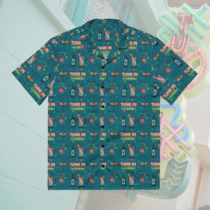Puede incluir: Camisa abotonada de color turquesa con un estampado repetido de copas de cóctel, botellas y el texto "TUNE IN". La camisa de manga corta tiene un cuello clásico y cierre de botones. El diseño presenta detalles en naranja, blanco y negro.