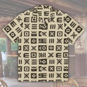 May include: A button-down shirt with a beige background and a repeating pattern of dark brown geometric shapes. The short-sleeved shirt has a collared neckline and is buttoned up the front.