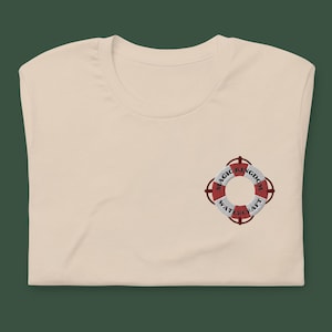 May include: A beige t-shirt with a red and white embroidered life preserver with the text "Magic Kingdom Watercraft" on it.