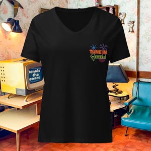 May include: Black v-neck t-shirt with a neon sign graphic that says "Tune In On Lounge".