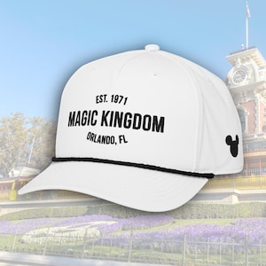 May include: White cap with black text reading "EST. 1971 MAGIC KINGDOM ORLANDO, FL." A black Mickey Mouse silhouette is on the side. The cap has a black rope detail along the brim.