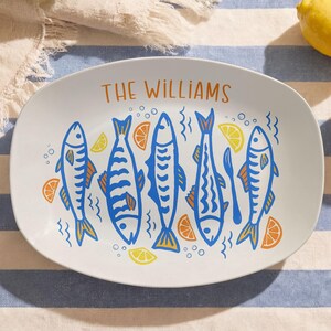 May include: White oval platter with a blue and orange fish design and the text "THE WILLIAMS". The platter features six stylized fish, lemon and orange slices. Two lemons are visible in the background.