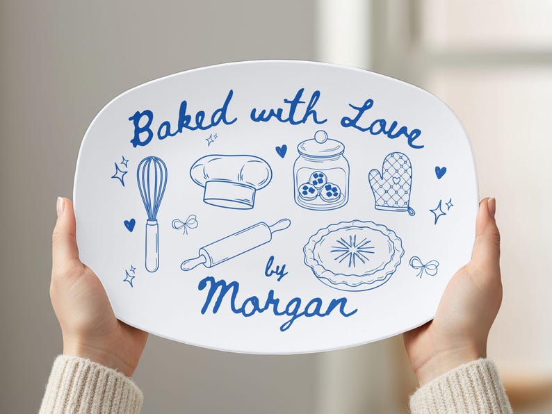 May include: White oval serving platter with blue illustrations of baking tools and the text "Baked with Love by Morgan." The design includes a whisk, chef's hat, rolling pin, pie, and oven mitt.