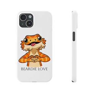 May include: A white smartphone case featuring a cartoon illustration of an orange bearded dragon making a heart shape with its hands, with its tongue sticking out. The text BEARDIE LOVE is printed in black below the lizard. A side view is shown.