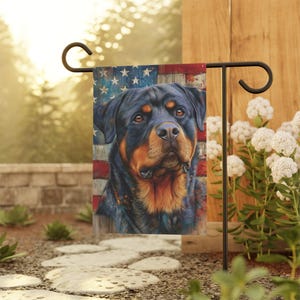 May include: A garden flag with a Rottweiler dog design and an American flag background. The flag shows a Rottweiler's portrait against the US flag, with red and white stripes and blue stars. It's mounted on a black metal stand, suitable for a garden.