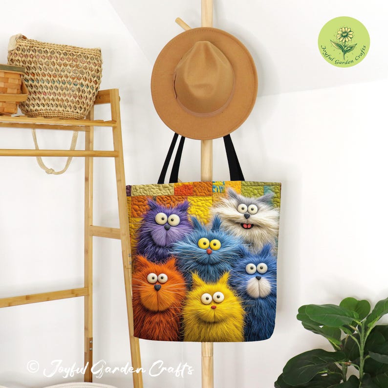 May include: A colorful tote bag featuring a group of six cartoon cats with fluffy fur in shades of orange, yellow, blue, and purple. The cats have large eyes and are set against a patchwork background. The bag is hanging on a wooden coat rack.