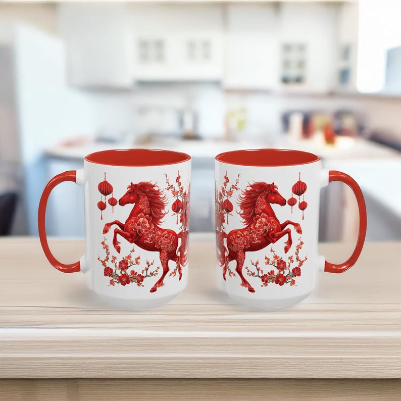 May include: Two white ceramic mugs with red interiors and handles. Each mug features a red horse design with floral and lantern accents. The mugs are on a light-coloured surface.