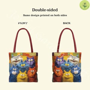 May include: Double-sided tote bag featuring a colorful design of cartoon cats. The bag has a burgundy handle and the same design is printed on both sides. The cats are in various colors, including blue, orange, purple, and yellow.