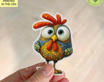 May include: A colorful cartoon sticker of a chicken with large blue eyes, a yellow beak, and red comb and wattle. The sticker is held by a hand. The text "PRINTED IN THE USA" is in the upper left corner.