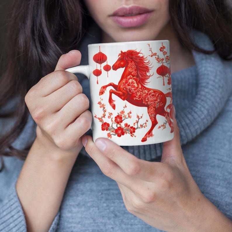 May include: White ceramic mug with a red horse design, floral patterns, and lantern accents. The horse is rearing up, with detailed floral patterns. Red lanterns and cherry blossoms decorate the mug, creating a festive and artistic look.