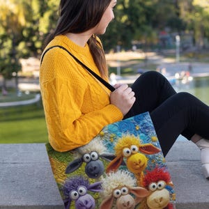 Puede incluir: Un bolso tote con una colorida ilustraci&oacute;n de ovejas de dibujos animados con lana de varios colores. El bolso tiene un fondo azul con estrellas amarillas y flores blancas. El bolso lo lleva una persona con un su&eacute;ter amarillo.