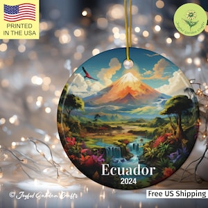 May include: A round ceramic bauble depicting a colourful landscape with a mountain, a waterfall, and lush greenery. The text "Ecuador 2024" is printed on the bauble.