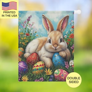 Peut inclure: Drapeau de jardin de Pâques recto-verso avec un lapin brun et blanc duveteux entouré d'œufs de Pâques colorés dans un champ de fleurs. Imprimé aux États-Unis.