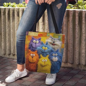 May include: A colorful tote bag featuring a whimsical design of six fluffy cartoon cats in various colors: purple, blue, orange, yellow, and gray. The cats have large eyes and expressive faces. The bag has black straps.