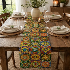 May include: A wooden dining table set for a meal, featuring a colorful patterned table runner. The runner displays a mosaic of geometric floral designs in shades of yellow, blue, red, and green. The table is set with plates, napkins, and wine glasses.