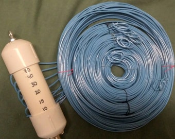 May include: A white antenna tuner with a blue wire coiled around it. The tuner has a dial with numbers from 10 to 80.