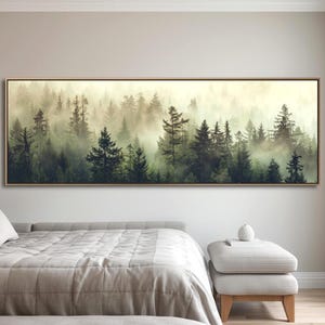 May include: A rectangular framed canvas print depicts a misty forest scene. The artwork showcases a dense forest of evergreen trees in varying shades of green, partially obscured by a layer of fog. The frame is a light brown color.
