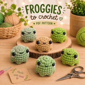 Puede incluir: Seis pequeñas figuras de ranas tejidas a ganchillo, redondas, en tonos verdes y beige, cada una con ojos de plástico negro y mejillas rosadas. El texto FROGGIES to crochet PDF PATTERN aparece arriba y una etiqueta dice Made with love.