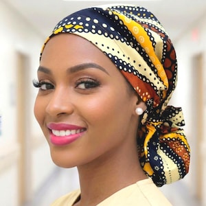 May include: A patterned head covering in navy blue, yellow, and brown with white polka dots and geometric shapes. The head covering is tied at the back. The person is wearing a light yellow top.