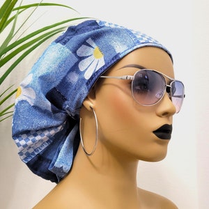 May include: A blue and white patterned surgical scrub hat with a daisy print. The hat is worn by a mannequin with silver hoop earrings and aviator sunglasses.