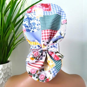Puede incluir: Un gorro de quirófano de patchwork colorido con un lazo en la parte posterior. El gorro está hecho de varias telas con patrones florales, a cuadros y a rayas.
