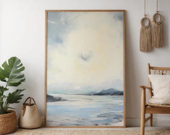 May include: An abstract landscape painting in a wooden frame. The artwork features a serene coastal scene with a light blue and yellow sky, a light blue sea, and dark blue mountains in the distance. The painting evokes a sense of calm.