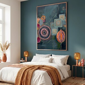 May include: Abstract art piece with a teal background, featuring geometric shapes in pink, orange, and blue. The artwork includes a large circular design and a framed border. The painting is displayed above a bed with white linens and a brown throw.