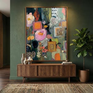 May include: Large framed abstract art print with a wooden frame. The artwork features a colorful floral design with pink, orange, and yellow flowers, and geometric shapes. The print is displayed above a wooden cabinet with decorative vases and a potted plant.